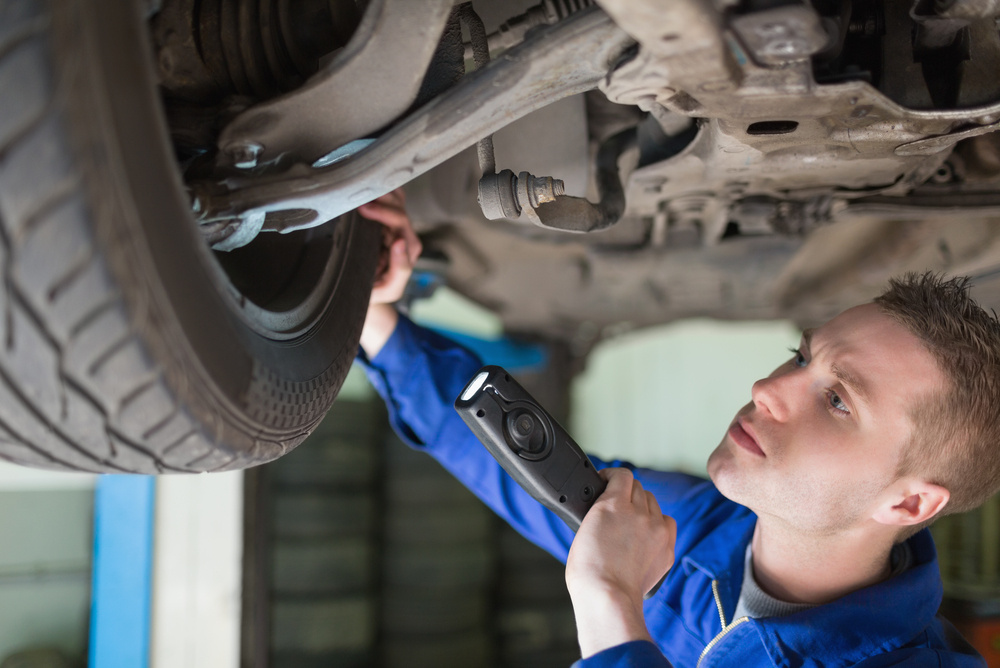 Male mechanic with flashlight examining tire