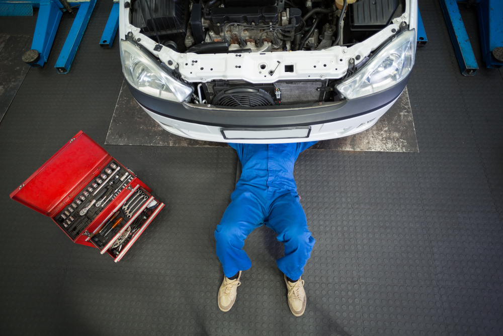 Mechanic lying and working under car at the repair garage